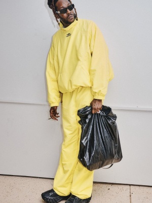 2 Chainz Wearing Balenciaga Black Wide Sunglasses With A Yellow Jacket And Pants Garbage Bag And Defender Sneakers