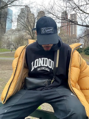 Rauw Alejandro Wearing A Raf Simons Hat With A Beige Puffer Jacket Balenciaga Paris Hoodie And Nike Pants