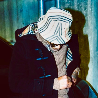 A Boogie Wearing A Burberry Icon Stripe Bucket Hat With A Burberry Coat