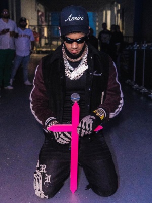 Anuel Aa Wearing An Amiri Varsity Jacket With Wes Lang Jeans Black Skeleton Gloves And A Black Trucker Hat