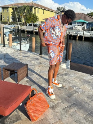 Boston Richey Wearing A Rhude Mosiac Knit Polo And Shorts With Nahmias Sneakers And A Goyard Bag