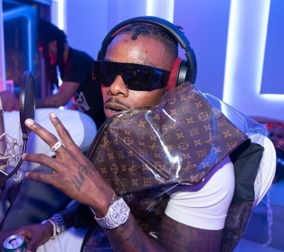 Dababy Wearing Louis Vuitton Black Sunglasses And Brown Inflatable Puffer With Amiri Shorts