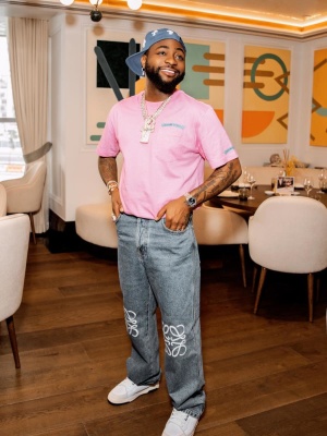 Davido Wearing A Chrome Hearts Light Blue Cross Trucker Hat And Pink Tee With Loewe Jeans And Puma Sneakers