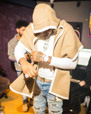 Fivio Foreign Wearing A Burberry Biege White Trim Hooded Cape With Plaque Check Belt And Amiri Biker Patch Jeans