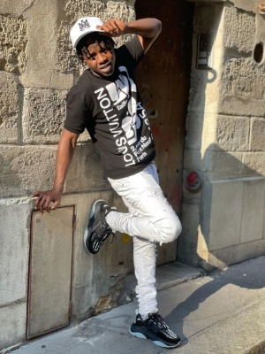 Jackboy Wearing An Amiri Ma Trucker Hat With A Louis Vuitton T Shirt Amiri White Mx1 Jeans And Black Skeleton Sneakers