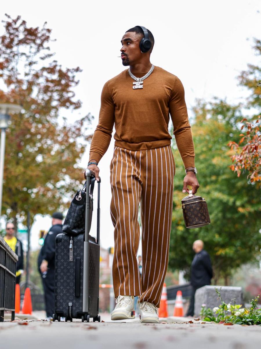 Jalen Hurts: Brown Sweater and Striped Pants & Louis Vuitton Monogram Luggage