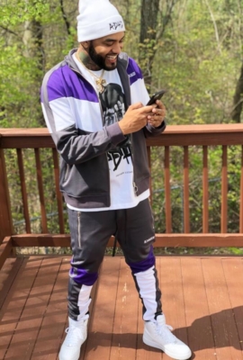 Joyner Lucas Wearing A Grey And Purple Track Jacket And Track Pants With White Adhd Beanie And T Shirt