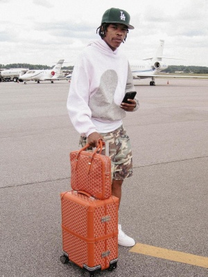 Lil Baby Wearing A Dior X Erl Hoodie With Camo Shorts And Goyard Bags