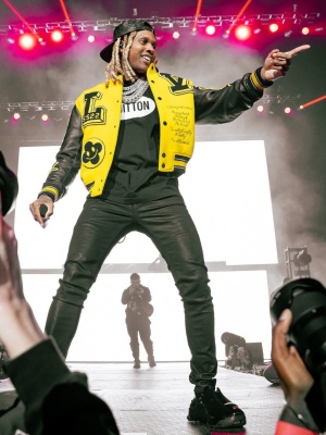 Lil Durk Performing At The Wells Fargo Center In A Louis Vuitton Denim Hat Yellow Varsity Jacket Black Oval Tee And Patent Black Sneakers