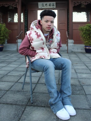 Lil Mosey Wearing A Moncler Tie Dye Puffer Vest And Purple Hoodie With Amiri Flared Jeans And Nike Air Force 1 Sneakers