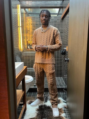 Lil Tjay Wearing A Brown Cable Knit Sweater And Pants With White Leather And Suede Sneakers
