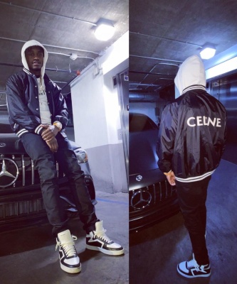 Lil Tjay Wearing A Celine Black Satin Varsity Jacket With A White Logo Hoodie And High Top Sneakers