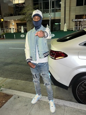 Lil Tjay Wearing An Amiri White Logo Trucker Hat With A Denim Bones Jacket Logo Applique Jeans And Skeleton Sneakers