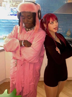 Lil Uzi Vert Wearing A Pink Trapper Hat With A Pink Long Sleeve Allover Logo Silk Shirt And Pants
