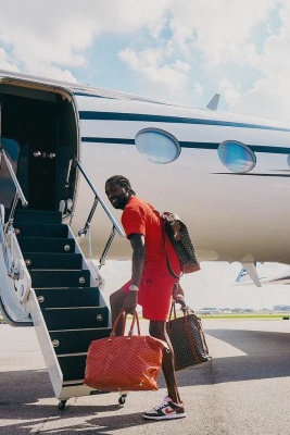 Meek Mill Wearing A Givenchy Orange Towel Tee And Shorts With Goyard Bags And Nike Dunks