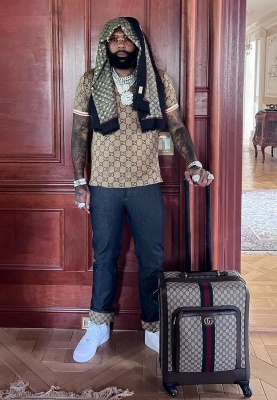 Money Man Wearig A Guccci Bees Scarf Beige Gg Polo Indigo Gg Cuff Jeans And A Gucci Rolling Suitcase