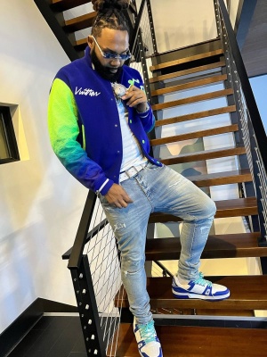 Money Man Wearing A Louis Vuitton Blue And Neon Green Varsity Jacket With A White Monogram Belt And White Blue Low Top Lv Trainer Sneakers