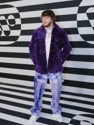 Mrda Beatz Wearing An Amiri Purple Shearling Jacket With Tie Dye Pants And Louis Vuitton Sneakers