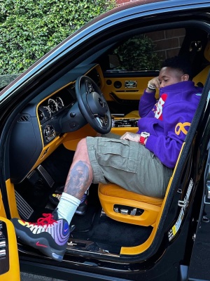 Mustard Wearing A Supreme New York Varsity Jacket With Cargo Shorts And Nike X Superme Sneakers