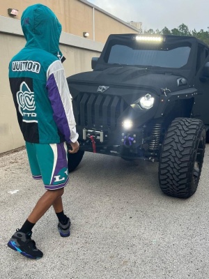 Nardo Wick Wearing A Louis Vuitton Teal And Purple Jacket With Matching Shorts And Grey Black High Top Sneakers