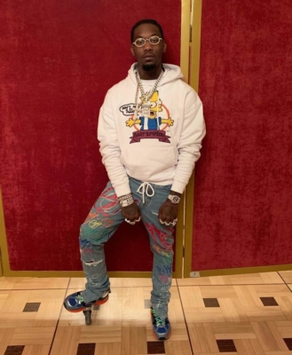 Off Set Wearing A White Off White Simpsons Hoodie With Off White Paint Splatter Jeans And Grey Blue And Orange Sneakers