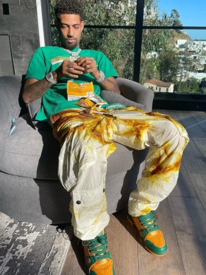 Pnb Rock Wearing A Palm Angels Crocodile Tee With White And Yellow Tie Dye Cargo Pants And Louis Vuitton Sneakers