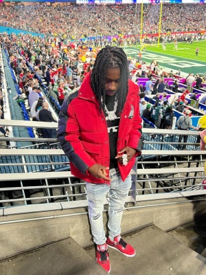Polo G At Super Bowl Lvii Wearing An Avirex Puffer With Amiri Mx1 Jeans And Jordan Red Sneakers