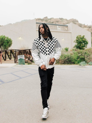 Polo G Wearing A Celine Checkered Windbreaker Jacket With Amiri Black Crystal Stripe Jeans And Louis Vuitton Silver Trainer Sneakers
