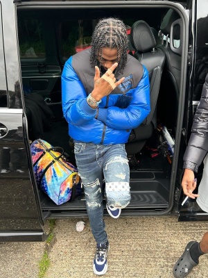 Russ Millions Wearing A Louis Vuitton Blue Puffer With Amiri Blue Art Patch Jeans Dior B22 Sneakers And A Lv Bag