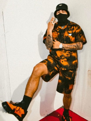 Ryan Castro Wearing A Prada Black Bucket Hat With An Orange Prada Shirt And Short And Cloudbust Thunder Sneakers