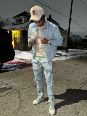 Skilla Baby Wearing A Rhude Light Blue Padded Jacket With A Givenchy Beige Tee Rhude Light Blue Pants And Rick Owens Sneakers