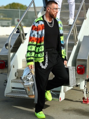 Travis Kelce Wearing A Louis Vuitton Mohair Cardigan With Clear Glasses A Metallic Silver Backpack And Briefcase With Nike X Off White Neon Sneakers