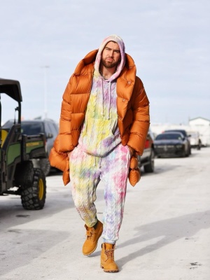 Travis Kelce Wearing A Rick Owens Orange Down Coat With A Camp High Tie Dye Hoodie And Sweatpants And Timberland Boots
