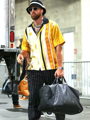 Travis Kelce Wearing Marni Sunglasses And Yellow Floral Shirt With A Bottega Veneta Bag