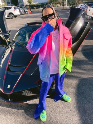 Tyga Wearing A Louis Vuitton Rainbow Gradient Monogram Leather Jacket With Blue Pants Louis Vuitton Neon Green Sneakers And Louis Vuitton Sunglasses