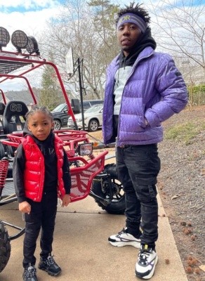 Yfn Lucci Wearing A Dior X Daniel Arsham Hoodie With A Purple Oblique Puffer Cargo Jeans And B22 Sneakers