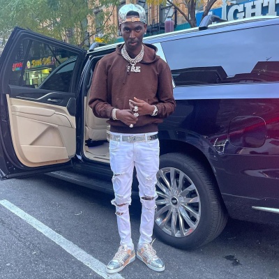 Young Dolph Wearing A Louis Vuitton Mirror Monogram Hat And Belt With A Brown Hoodie And Metallic Sneakers
